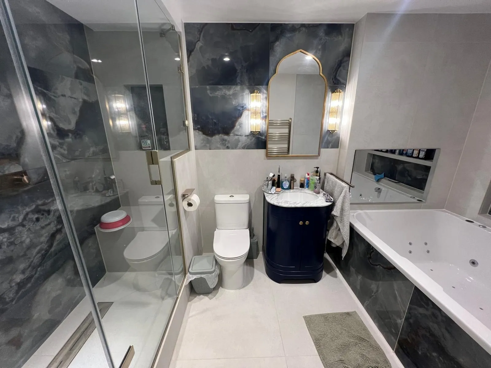 Bathroom with blue onyx-effect feature wall, glass shower screen and whirlpool bath