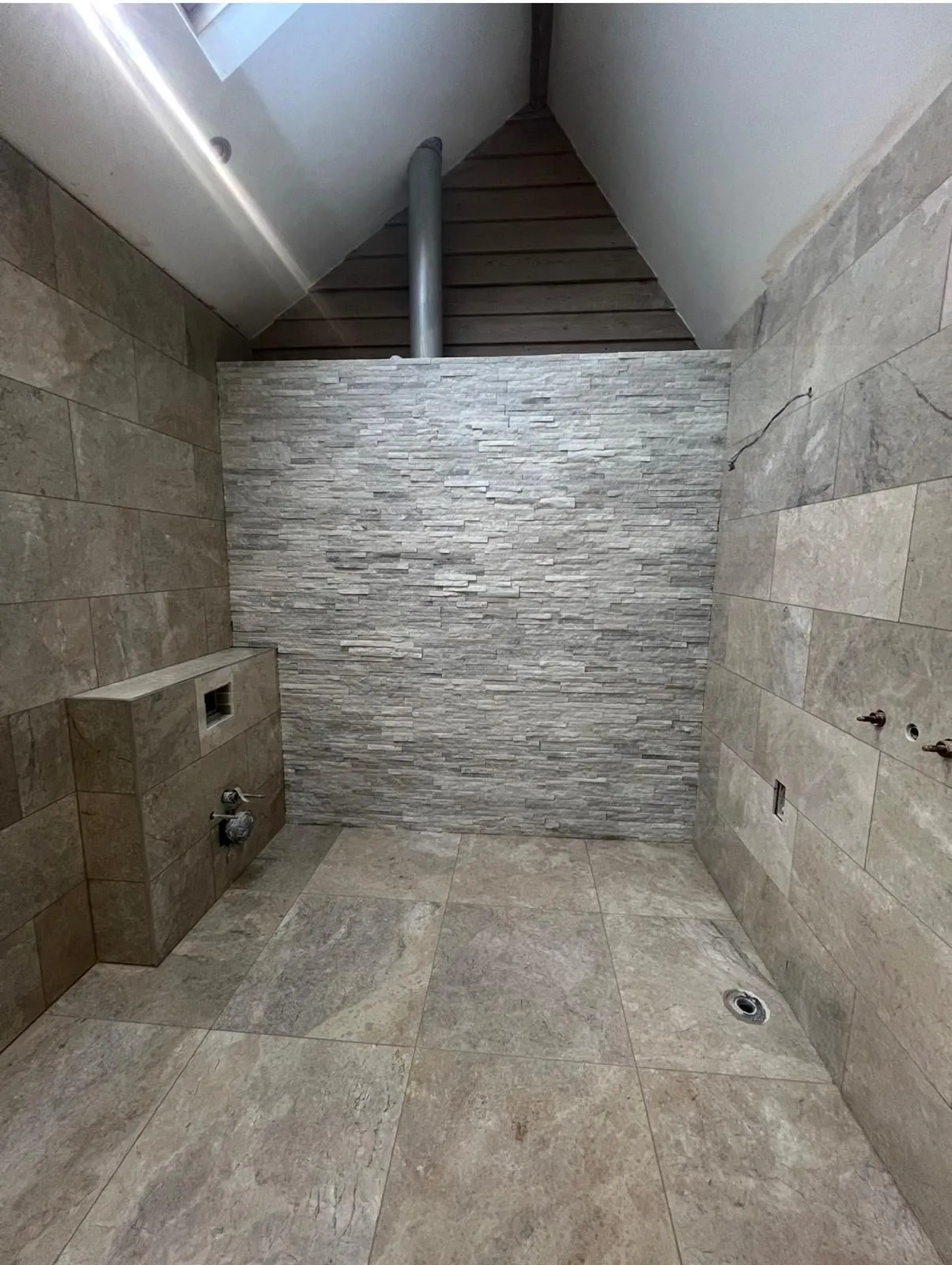 Loft wet room with a split-face stone wall and stone-effect floor